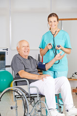 Krankenschwester misst Blutdruck bei Mann im Rollstuhl