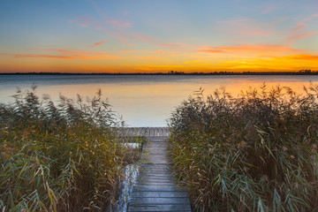 Orange Sunset over Jetty on the shore of a Lake