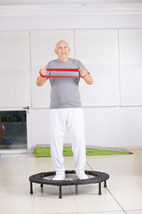 Alter Mann mit Gymnastikband auf Trampolin