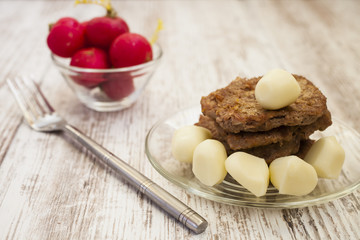 cutlets, cheese slices and a garden radish on a table