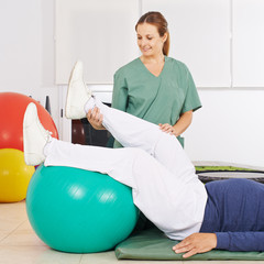 Physiotherapeut bewegt Bein bei Krankengymnastik