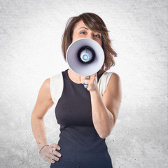 Fototapeta premium Pretty girl shouting with a megaphone over white background