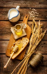 Fotobehang Honey in a jar, slice of bread, wheat and milk on vintage wood © pinkyone