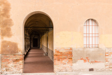 Rounded cloister entry and window with red iron grate
