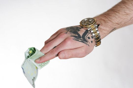 tätowierte Hand mit Luxusuhr hält 100-Euro-Schein