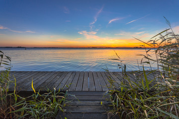Fototapeta na wymiar Blue and Orange Sunset over Boardwalk on the shore of a Lake