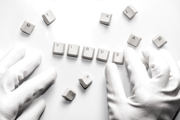 Hands with gloves typesetting virus with white keys on white.