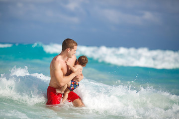 Young father with a young son play near the ocean.