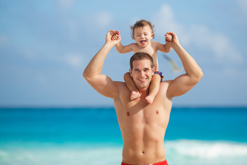 Fototapeta premium Young father with a young son play near the ocean.