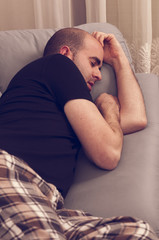 Young man sleeping in the sofa, watching tv