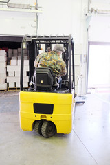 Worker driver stacking boxes by forklift stacker loader