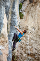 Fototapeta premium Rock climber climbing up a cliff