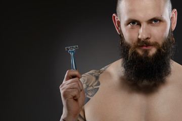 Muscular man with a beard holding a razor