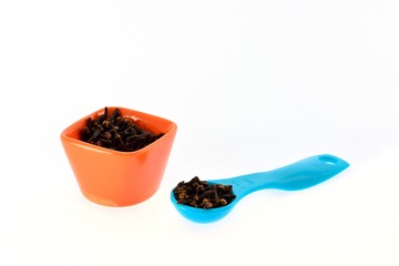 Fototapeta na wymiar Spice cloves in a cup and measuring spoon