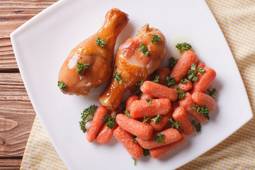 Roasted chicken legs and glazed carrots horizontal top view