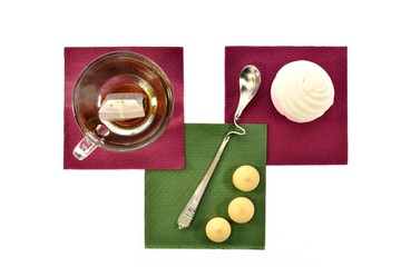 Fototapeta na wymiar Cup of black tea with a spoonful marshmallows on napkins