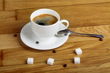 Hot fresh coffee in a white cup with sugar on wooden table
