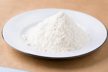 Fototapeta na wymiar Heap of wheat flour on white plate