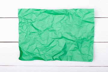 color crumpled paper on white wooden background. Green color.
