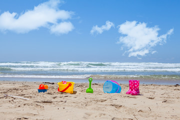 Colorful plastic beach toys lying on the beach sand