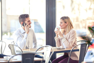 Two young businesspeople on coffee break in a cafe