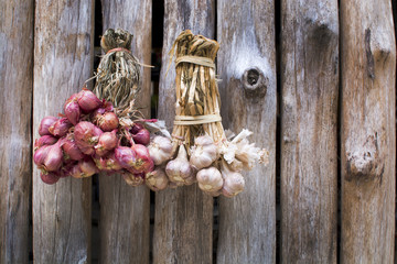 Red onions and garlics hanging on wood wall