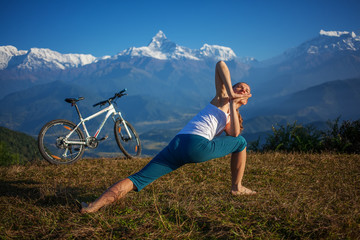 woman practicing yoga, relaxing after riding bikes high in mount