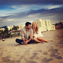 cute couple on beach cuddling while watching sunset