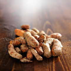 pile of fresh turmeric roots on wooden table with copyspace