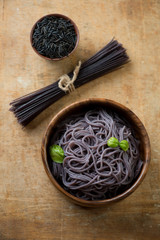 Black rice noodles over rustic wooden background