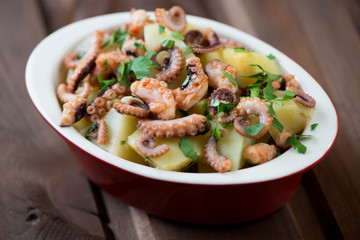 Octopus salad in a glass bowl, close-up, selective focus