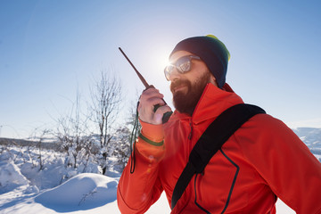 Rescue man talking with portable radio on mountain snow landscap - obrazy, fototapety, plakaty