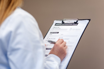 Female doctor compiling medical information form in medical cent