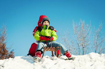 Two kids sliding with sledding in the snow.