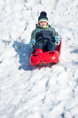 Fototapeta na wymiar Young kid sliding with bob in the snow.