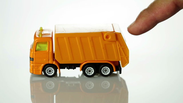 Orange toy garbage truck rolling into the scene