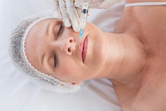 Woman receiving cosmetic injection on her lips