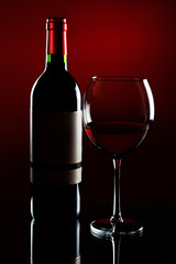 Elegant red wine glass with bottle on graduated red background