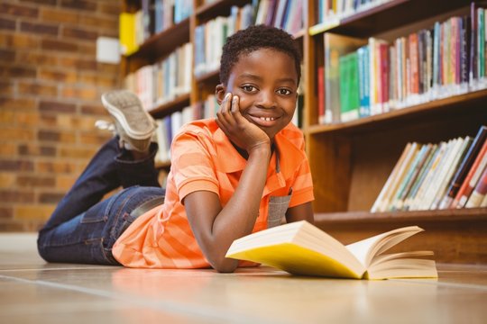 Cute boy reading book in library