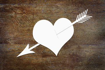 Heart pierced by an arrow on wooden background