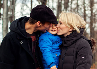 Fototapeta premium Loving parents kissing their son in the nature