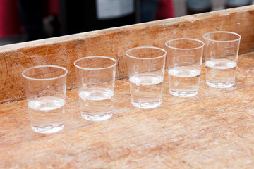 Row of shot glasses with vodka on wooden board.