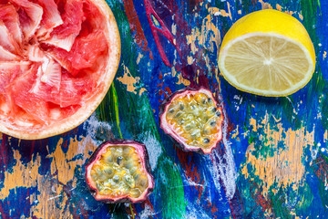 Passion fruit, lemon and grapefruit halves on a colorful backgro