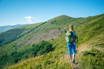Naklejka na ściany i meble Young woman hiking in the mountains
