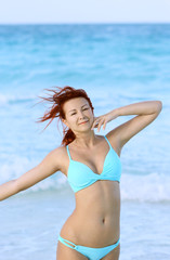 The redhead happy young woman standing at the ocean shore