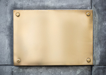 blank gold or brass metal sign or nameboard on concrete wall