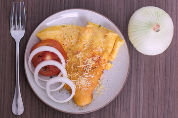 Dish of omelette with parmesan cheese, a fork and an onion