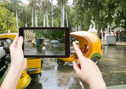 tourist taking photo of Havana street in rain