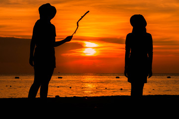 Happy woman silhouette standing against sunset with arms raised