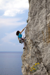 Female climber climbs wall in over the sea